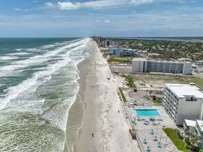 Ein Küstenhotel mit Blick auf den Strand, einem Swimmingpool und einem Parkplatz.
