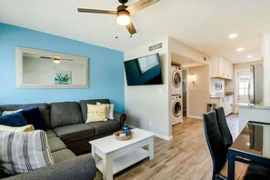 Ein modernes Wohnzimmer mit Sofa, Couchtisch, Fernseher und Deckenventilator.