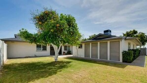 Ein eingeschossiges Haus mit Garage, Rasen und einem Baum mit gelben Blüten.