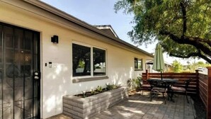 Ein Haus mit einer Terrasse, einem schwarzen Tor und einer Ziegelmauer.