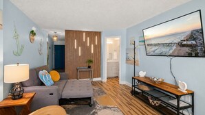 Ein Wohnzimmer mit einer Couch, einem Couchtisch, einem Fernseher und Holzboden.