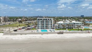 Ein Hotel an der Küste mit Pool, Strand und Parkplatz.