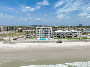 Ein Hotel an der Küste mit Pool, Strand und Parkplatz.