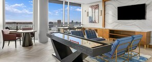 Ein modernes Wohnzimmer mit Poolbillard, bequemen Sitzgelegenheiten, einem Flachbildfernseher und Blick auf die Stadt.
