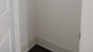 A corner of a room with a white door, a white wall, and a white closet with a metal rod.