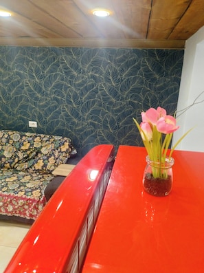 Una habitación con pared de diseño, una mesa roja y un florero con flores.