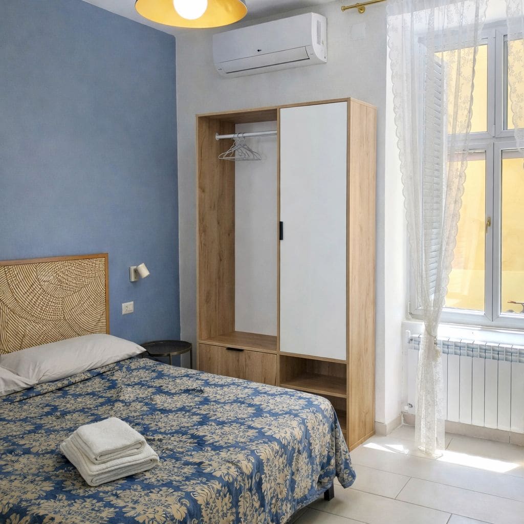 A bedroom with a bed, a wardrobe, a radiator, and a window with curtains.