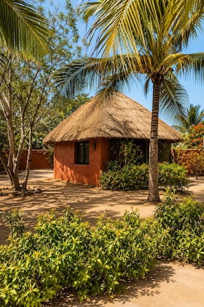 A thatched-roof hut with a dirt ground, surrounded by greenery and palm trees. - Large Villa - Private Pool - Ideal for Families and Groups (Ngaparou)