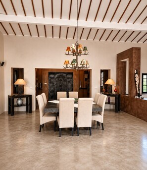 A spacious dining area with a high ceiling, a central chandelier, and a large wooden door. - Large Villa - Private Pool - Ideal for Families and Groups (Ngaparou)