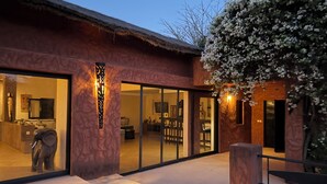 A modern building with large glass doors, a thatched roof, and a well-lit entrance.