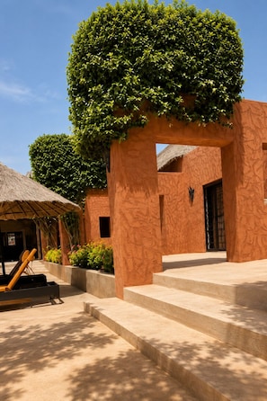 A building with a thatched-roof structure, a staircase leading to an entrance, and a well-maintained garden area. - Large Villa - Private Pool - Ideal for Families and Groups (Ngaparou)