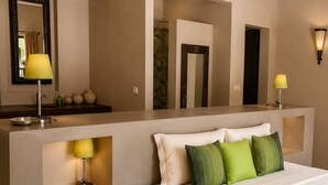 A modern bedroom with a large bed, a nightstand, a mirror, and a wall-mounted lamp.