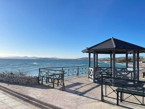 A coastal gazebo with a view of the sea, a stone wall, and a paved walkway. - Upscale Sea-View Apartment in Athenian Riviera (Paleo Faliro)