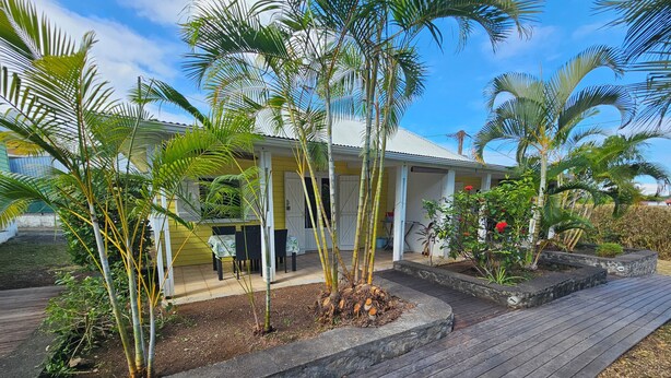 A house with a covered porch, a wooden deck, and various plants. - Ti kaz village Bungalow N°4 (Saint-Louis)