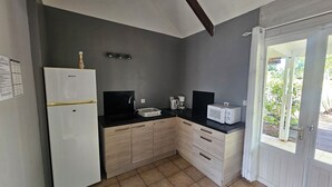 A compact kitchen with a refrigerator, microwave, sink, and wooden cabinets. - Ti kaz village Bungalow N°4 (Saint-Louis)