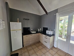 Eine kleine Küche mit Kühlschrank, Mikrowelle, Spüle und Holzschränken.