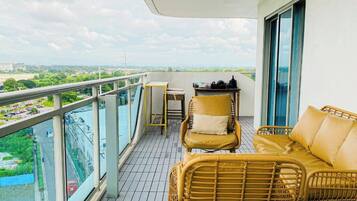 A balcony with wicker furniture, a table, and a view of a cityscape.