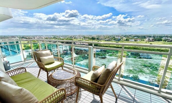 A balcony with wicker furniture and a view of a cityscape. - Family One Bedroom with Manmade Beach View & Mt Arayat View (San Fernando)