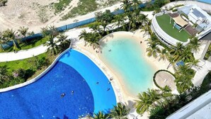 Un complexe hôtelier doté d’une grande piscine, d’une plage et de palmiers.