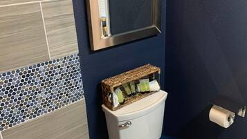 A bathroom with a toilet, a mirror, and a toilet paper holder.