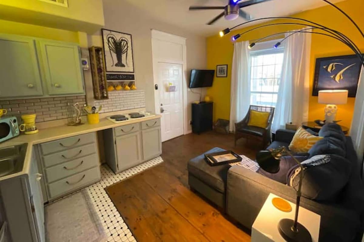 A compact living space with a kitchenette, a sofa, a television, and a ceiling fan.