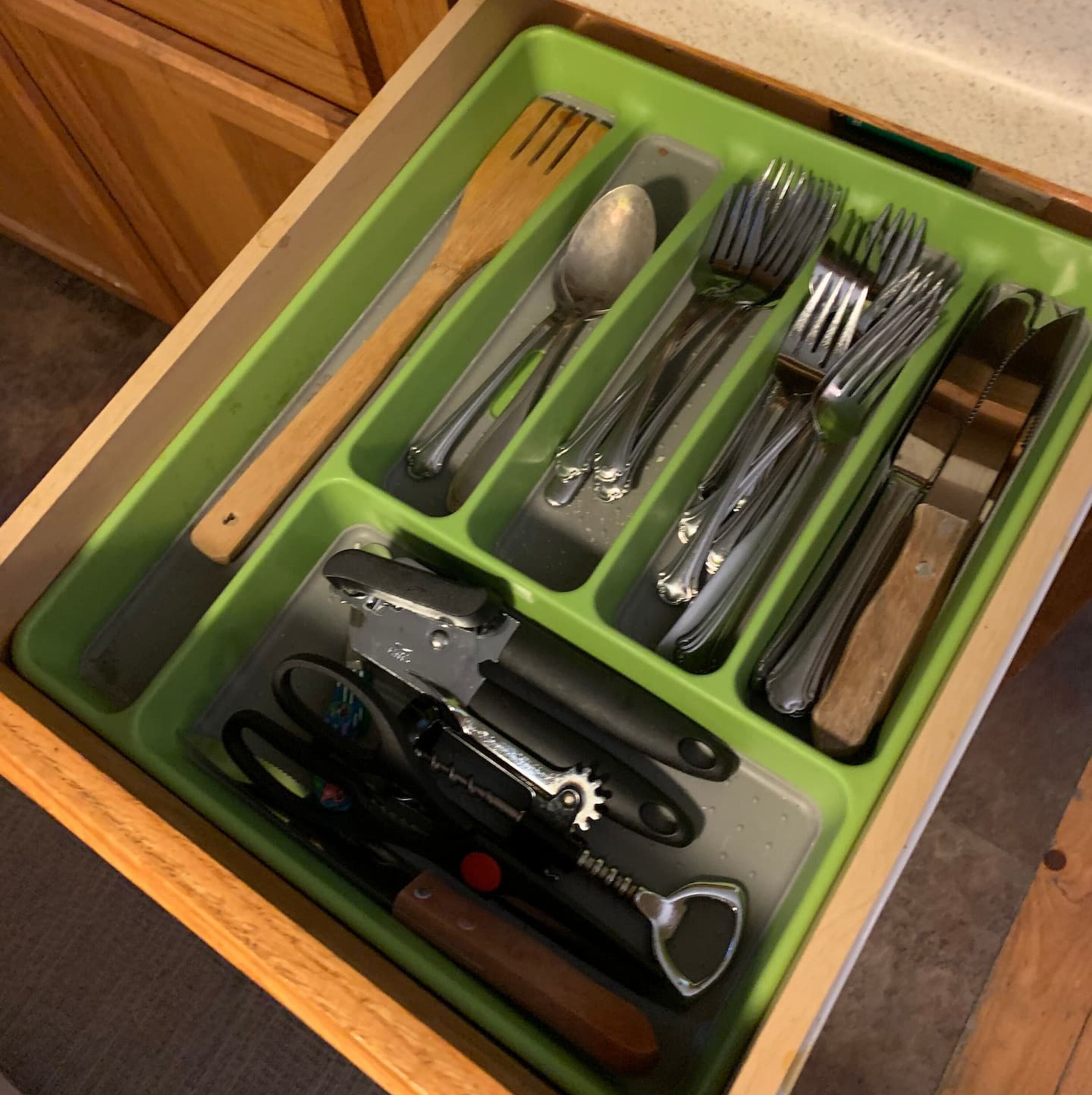 A drawer with compartments containing various kitchen utensils.