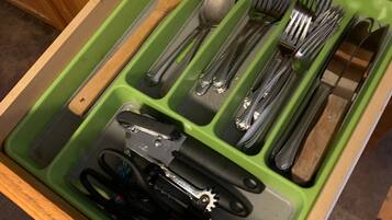 A drawer with compartments containing various kitchen utensils.