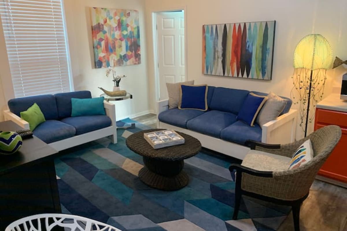 A living room with a blue sofa set, a coffee table, and a wicker chair.