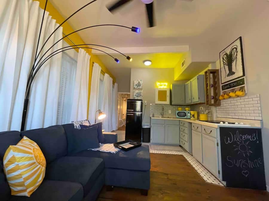 A modern living room with a sofa, a coffee table, and a view into the kitchen.