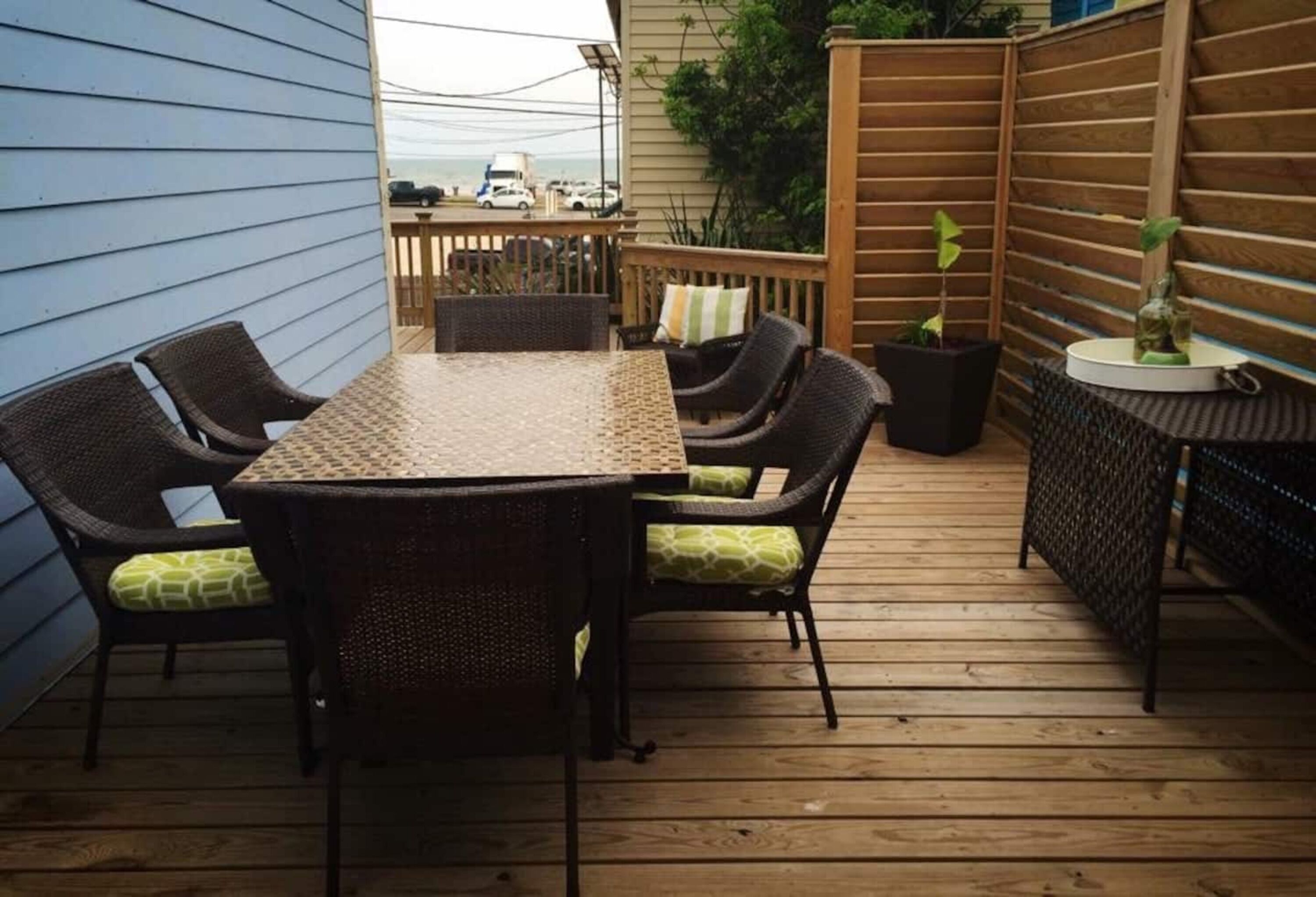 A covered patio with a table and chairs, a wooden fence, and potted plants.