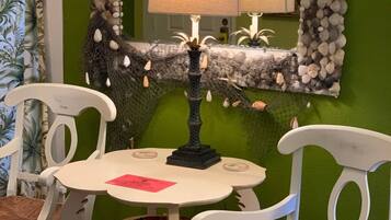 A dining area with a round table, white chairs, a decorative lamp, and a green wall.