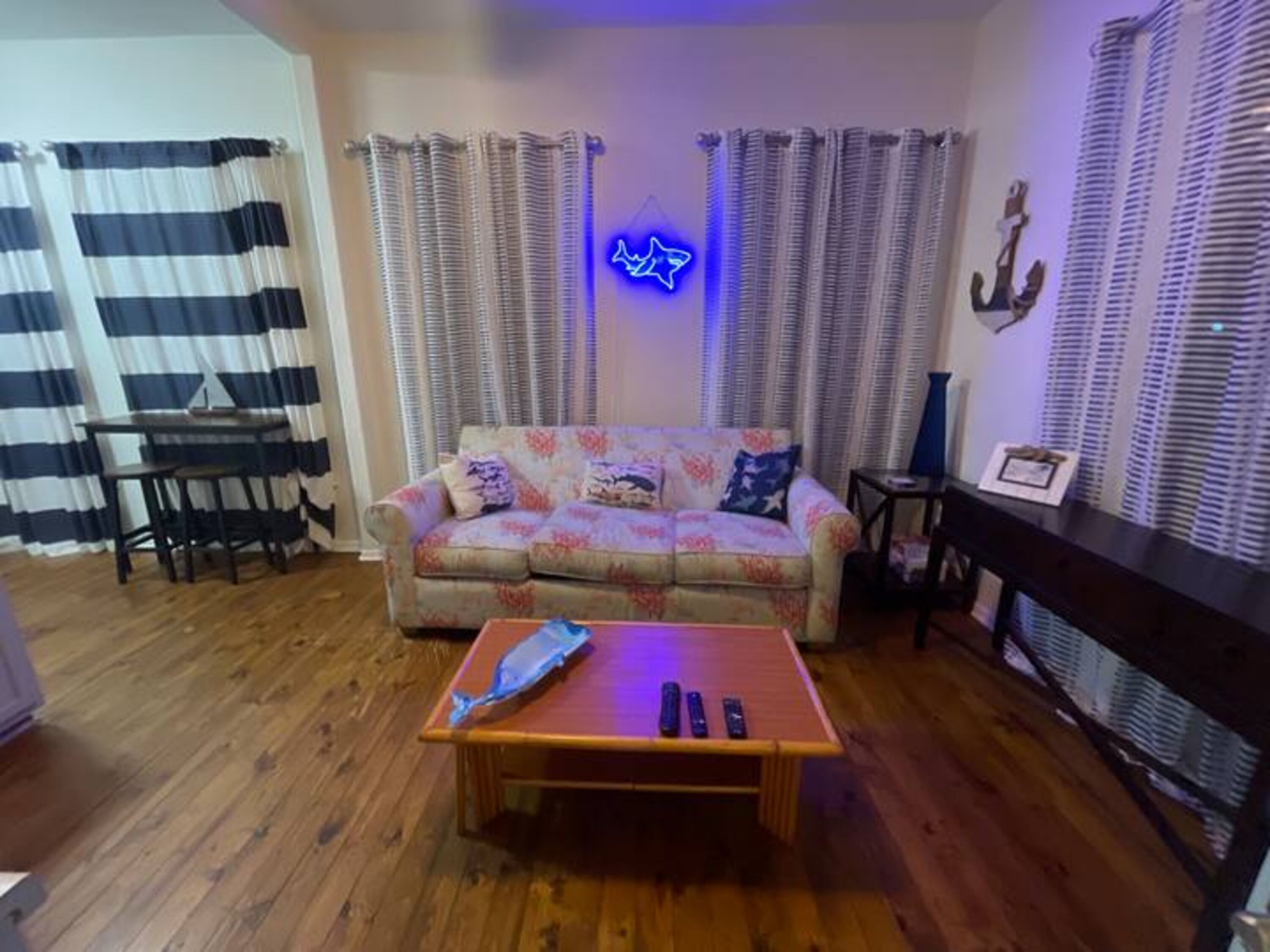 Un salon avec un canapé, une table basse, un meuble pour la télévision et des rideaux.