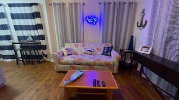 Un salon avec un canapé, une table basse, un meuble pour la télévision et des rideaux.