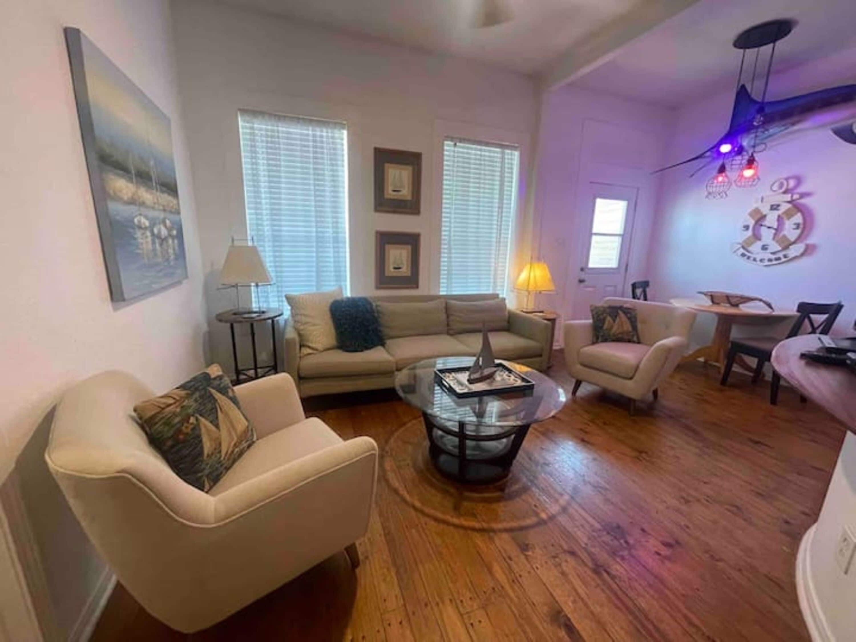 A living room with a sofa, armchair, coffee table, and a dining area with a table and chairs.