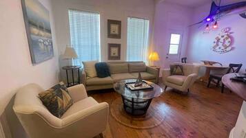 A living room with a sofa, armchair, coffee table, and a dining area with a table and chairs.