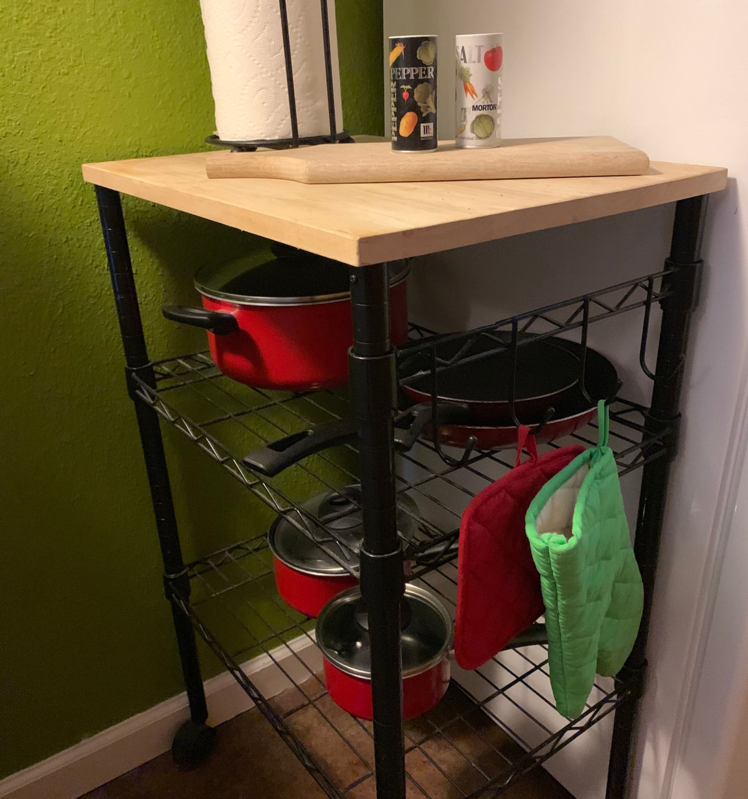 A kitchen cart with pots, a rolling pin, and a salt shaker.