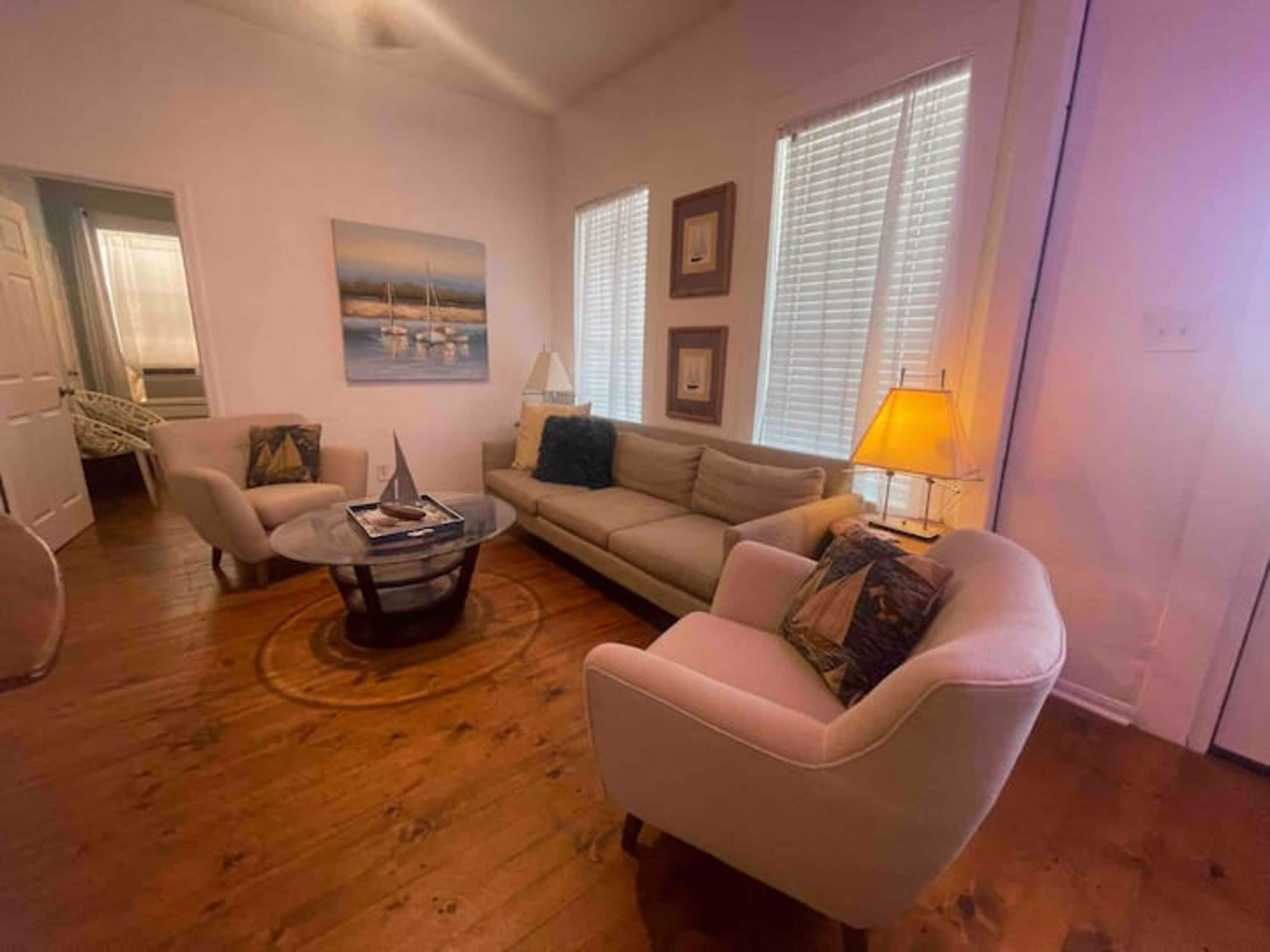 A living room with a sofa, armchair, coffee table, and a lamp.