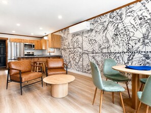 A modern kitchen with stainless steel appliances, wooden cabinets, and a dining area with a round table and chairs. - NEW Cabin Ellinor: Sauna, Starlink, Firepit, BBQ (Beaver)
