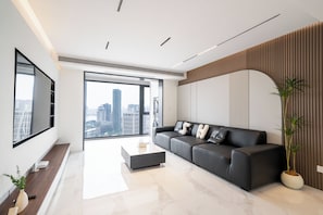 Una sala de estar moderna con un sofá de cuero negro, una mesa de centro y un ventanal con vista a la ciudad.