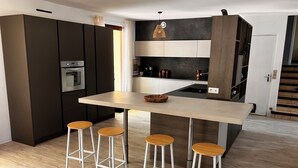 Une cuisine moderne dotée d’un îlot central, de tabourets de bar et d’appareils électroménagers intégrés.