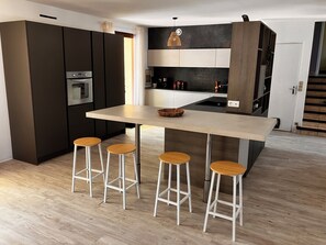 Eine moderne Küche mit Kochinsel, Barhocker und integrierten Geräten.