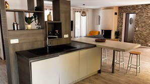 Une cuisine moderne dotée d’un îlot central intégré, d’un coin repas avec des tabourets et d’un mur d’accent en pierre.