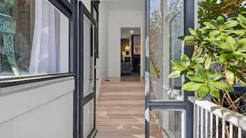 Un couloir avec un plancher en bois, une porte en verre et une plante en pot.