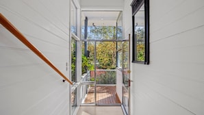 A modern interior with a wooden staircase leading to a balcony with a view of trees. - Perrins House Daylesford (Daylesford)