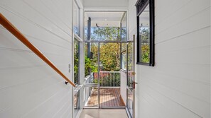 Ein modernes Interieur mit einer Holztreppe, die zu einem Balkon mit Blick auf Bäume führt.