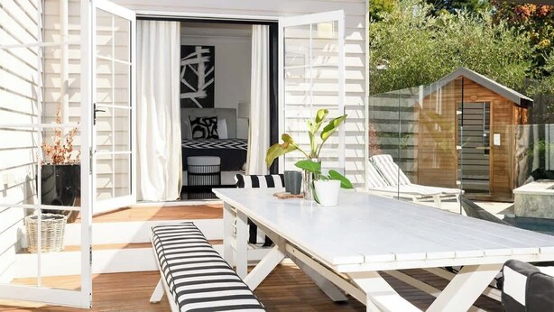 Een open terras met een eettafel, een bank en potplanten.