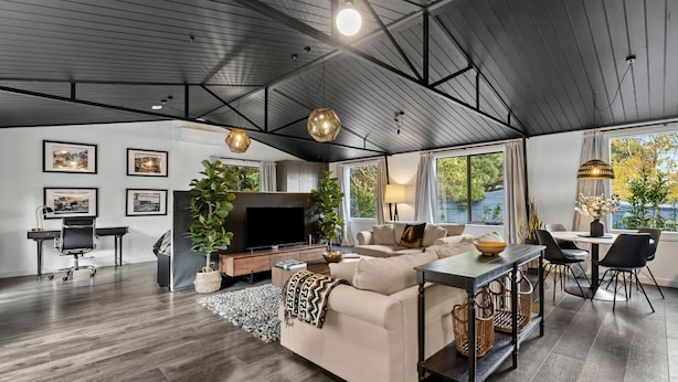 A modern living room with a sofa, TV, and dining area.