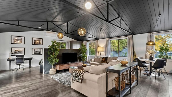 A modern living room with a sofa, TV, and dining area.