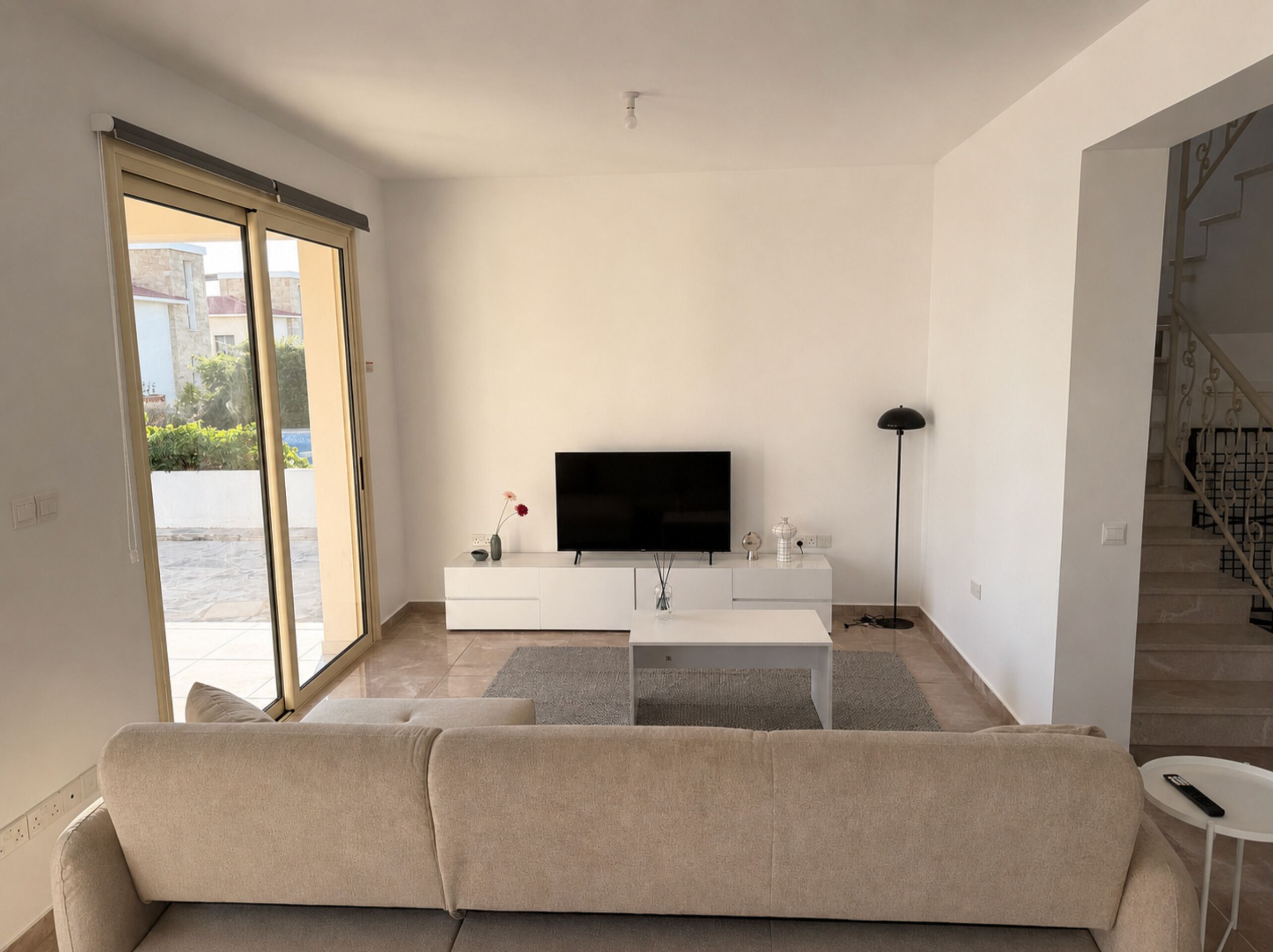 Ein modernes Wohnzimmer mit einer Couch, einem Fernseher und einer Treppe.