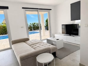 Un dormitori modern amb un llit sofà, una televisió, un escriptori i vista a una piscina.